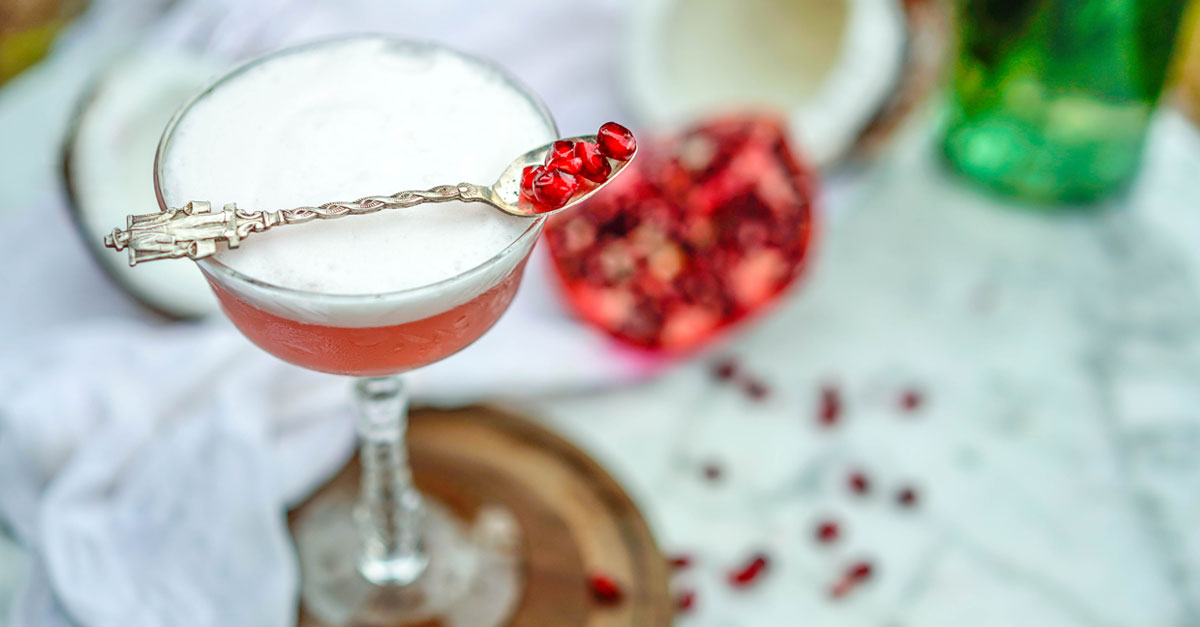 Wintry pomegranate and tropical coconut come together in this white rum sour. Learn how to make the cocktail and its toasted coconut syrup with this recipe!