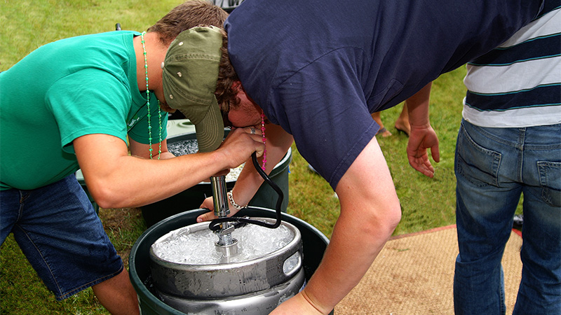 College students drinking from a beer keg.