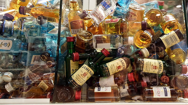 Duty Free shops often sell shooters and nips of alcohol. Despite this you cannot open them on your flight in the United States.
