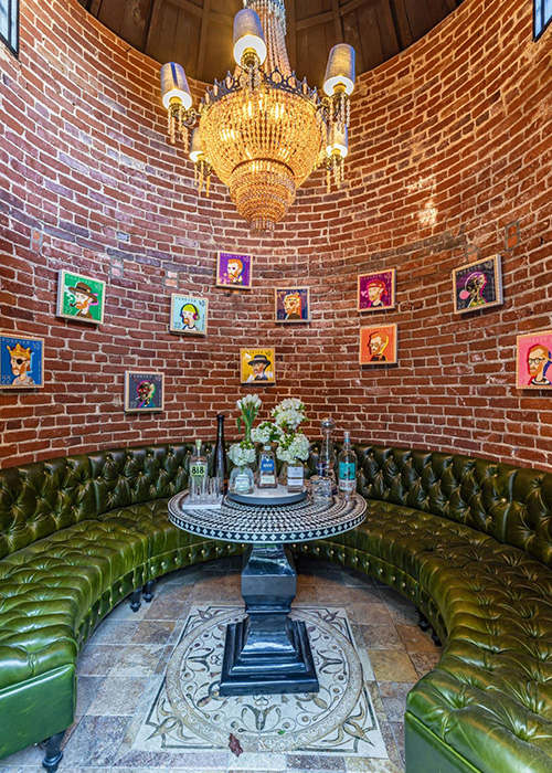 Una sala de degustación con un gran sofá verde redondo y obras de arte en las paredes.